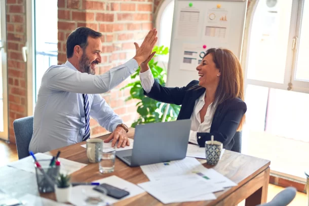 Mature colleagues high-fiving in meeting